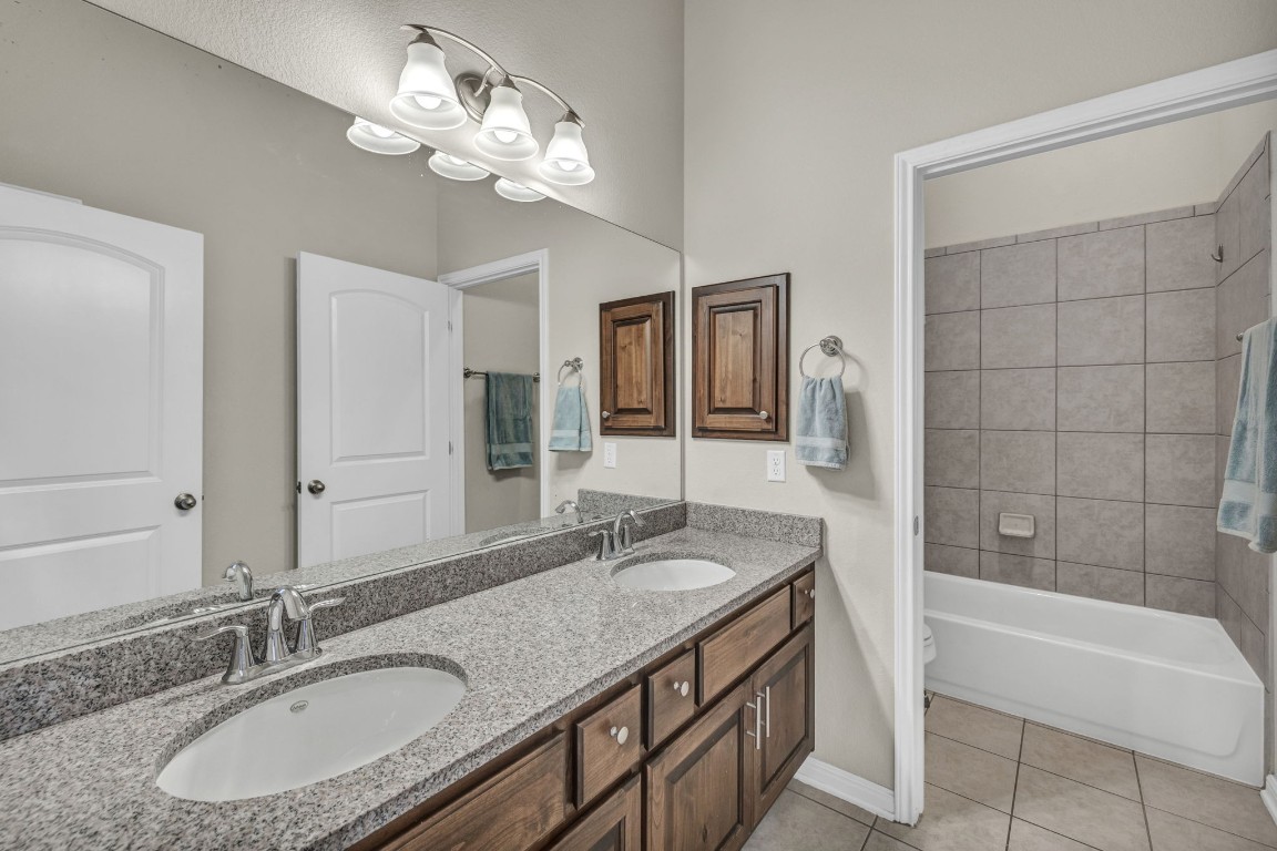 3821 Tordera Drive Austin, TX 78738 - Photo 17 of 30 a bathroom with a granite countertop double vanity sink a mirror and a bathtub