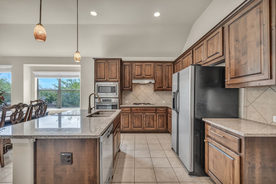 3821 Tordera Drive Austin, TX 78738 - Photo 8 of 30 a kitchen with granite countertop a refrigerator stove top oven and kitchen island