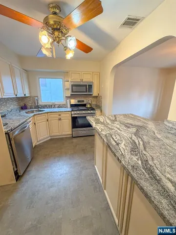 a kitchen with stainless steel appliances granite countertop a sink dishwasher stove and refrigerator
