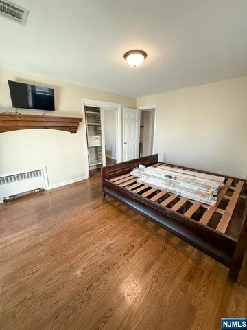 a bedroom with wooden floor and bed