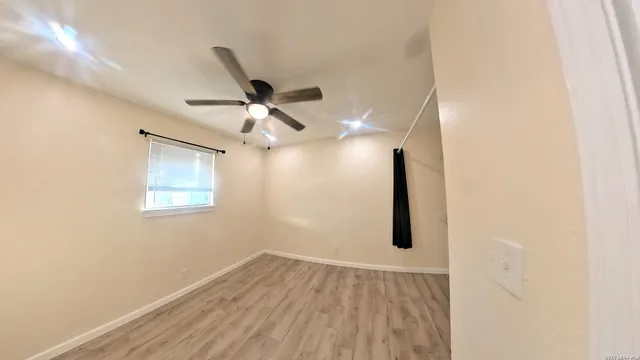 an empty room with wooden floor chandelier fan and windows
