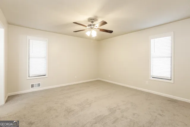 an empty room with windows and fan