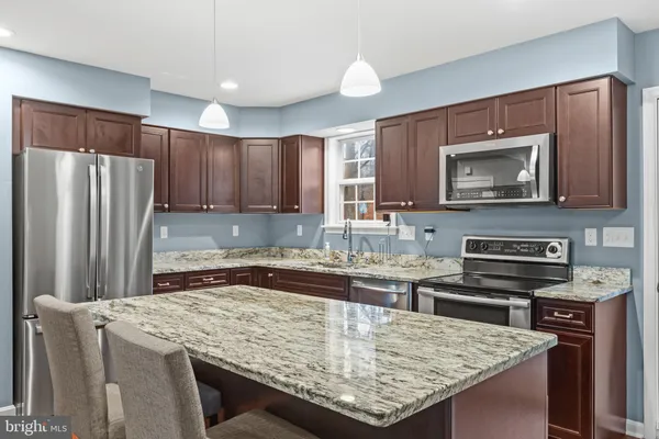 a kitchen with kitchen island granite countertop wooden cabinets refrigerator and stove