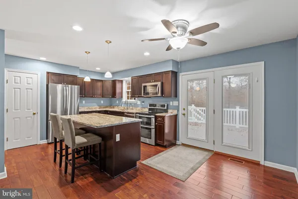 a kitchen with stainless steel appliances granite countertop a stove top oven a refrigerator a sink and a dining table with wooden floor