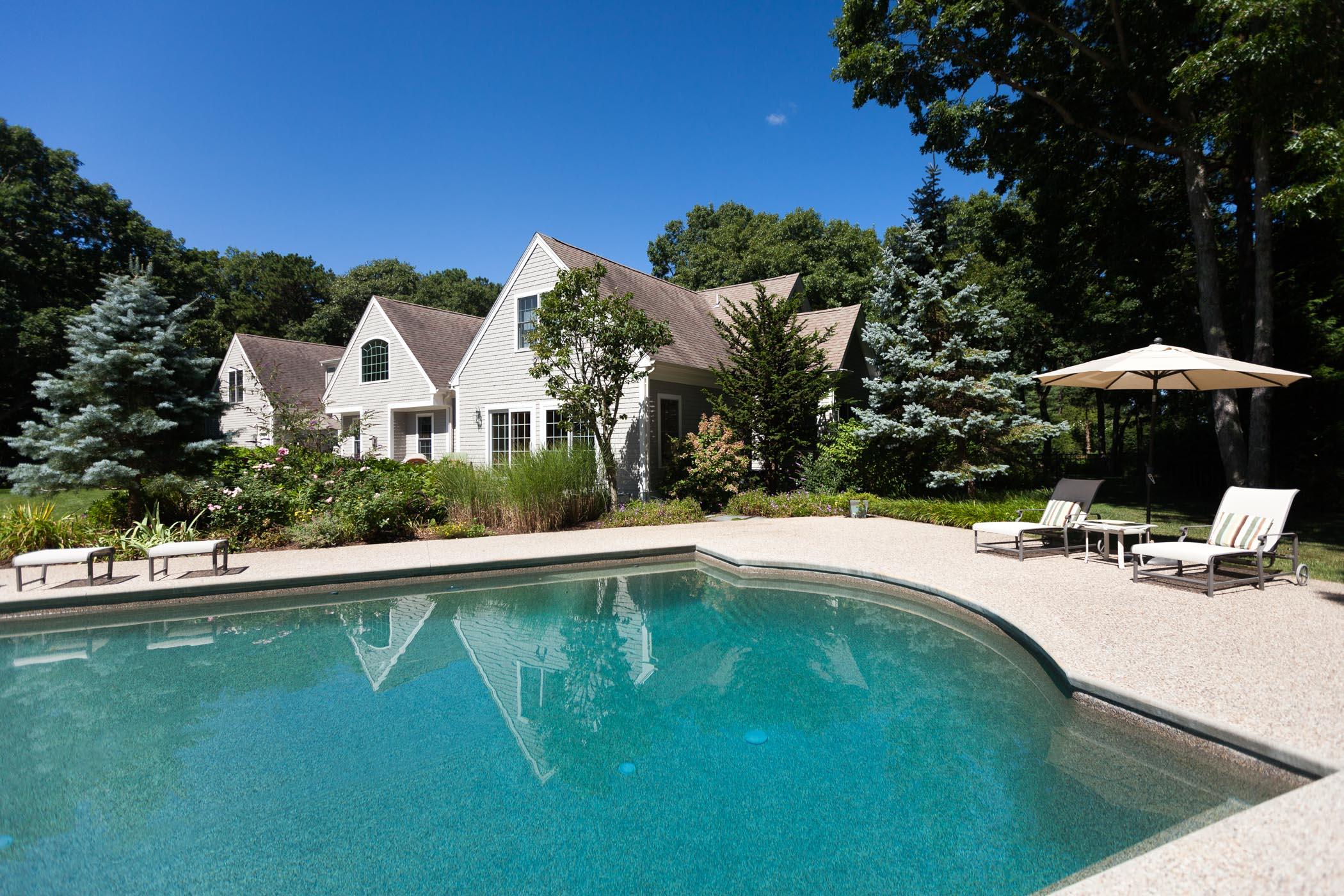 91 Great Bay Road Osterville, MA 02655 - Photo 23 of 27 a view of a swimming pool with lawn chairs under an umbrella