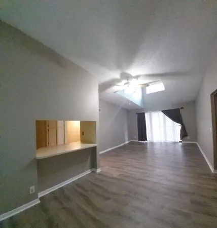 a view of an empty room and wooden floor cabinet and a window