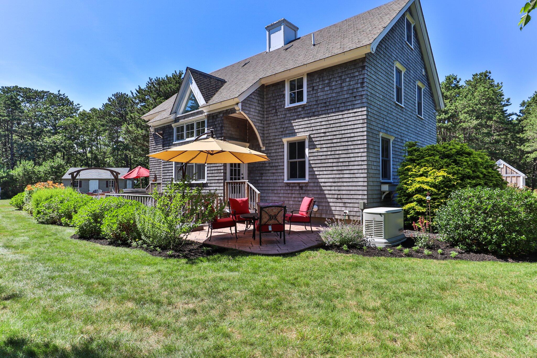 730 Slough Road Brewster, MA 02631 - Photo 78 of 87 a backyard of a house with table and chairs under an umbrella