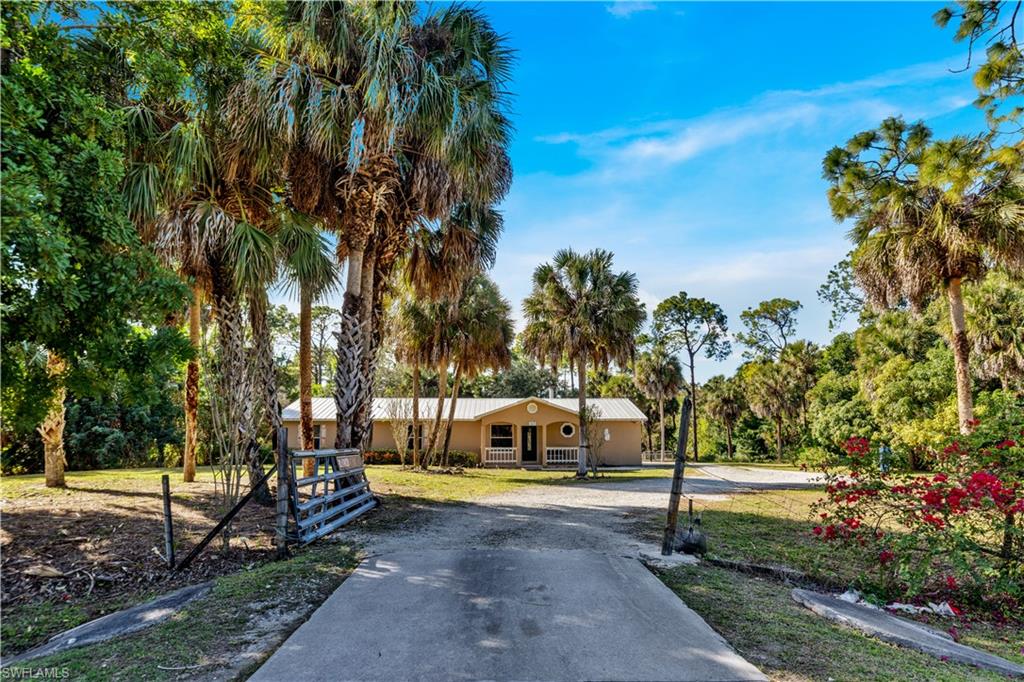 1867 17th Street Southwest Naples, FL 34117 - Photo 2 of 31 View of front of house with driveway, stucco siding, a metal roof, a front yard, and covered porch