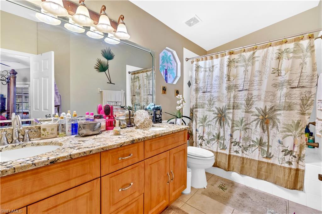 1867 17th Street Southwest Naples, FL 34117 - Photo 21 of 31 Bathroom with double vanity, shower / bath combination with curtain, light tile patterned floors, and lofted ceiling