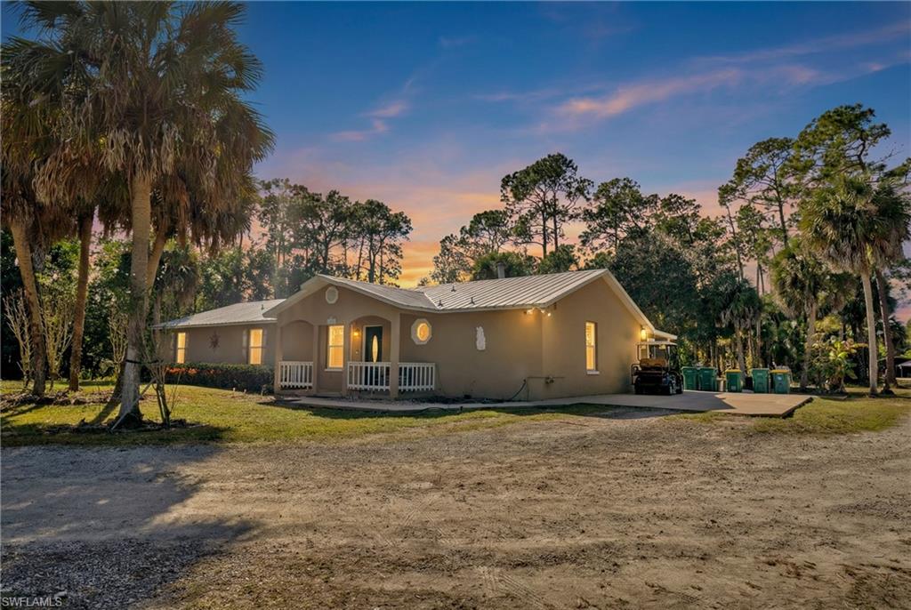 1867 17th Street Southwest Naples, FL 34117 - Photo 3 of 31 View of front of property featuring a standing seam roof, stucco siding, covered porch, and a front lawn