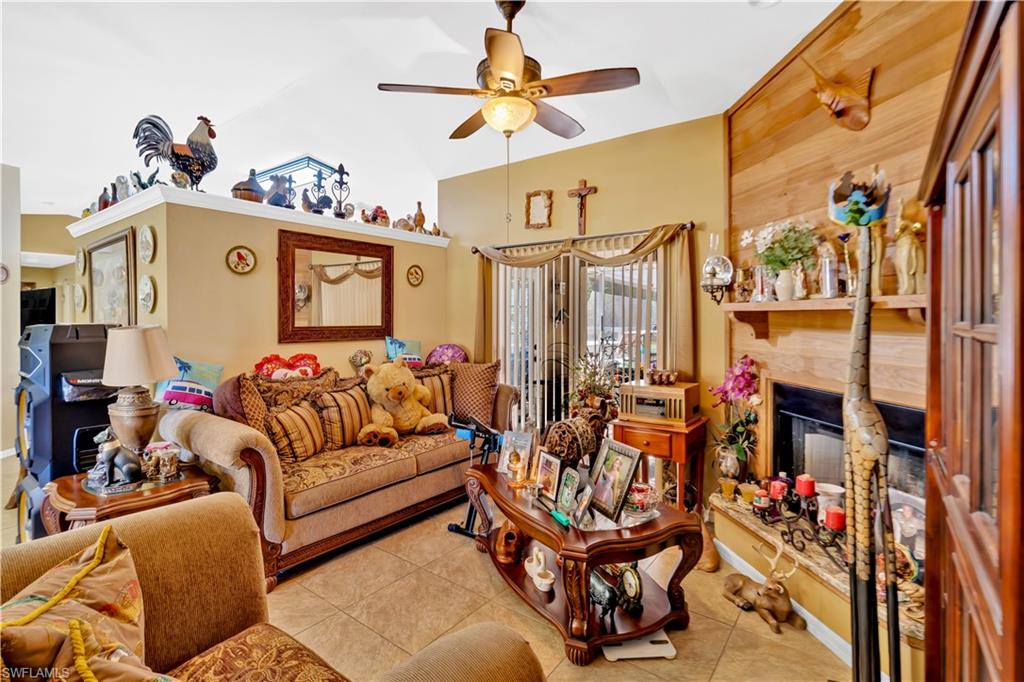 1867 17th Street Southwest Naples, FL 34117 - Photo 8 of 31 Tiled living room with a glass covered fireplace, ceiling fan, and lofted ceiling
