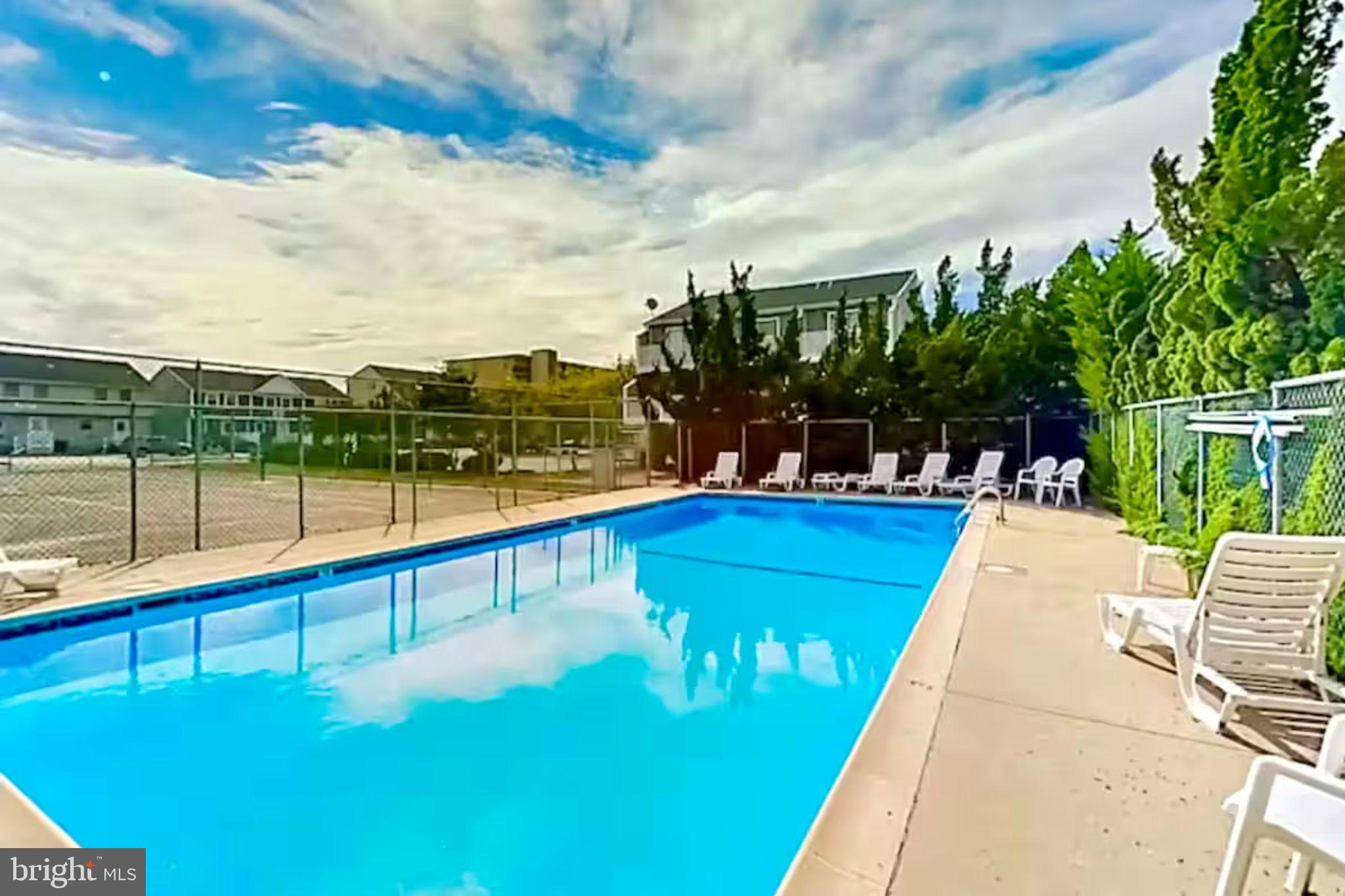 169 Jamestown Road, Unit 503 Ocean City, MD 21842 - Photo 18 of 18 a view of swimming pool with a bench and trees in the background