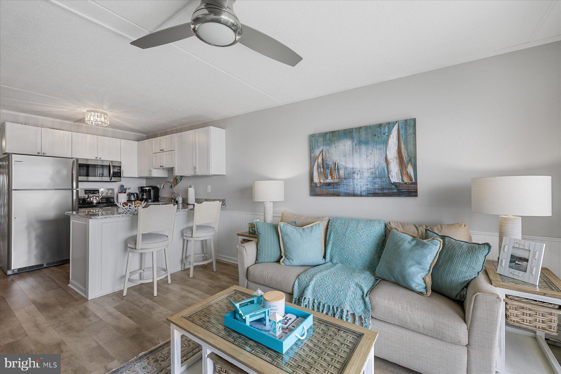 169 Jamestown Road, Unit 503 Ocean City, MD 21842 - Photo 5 of 18 a living room with white couches and a dining table with kitchen view