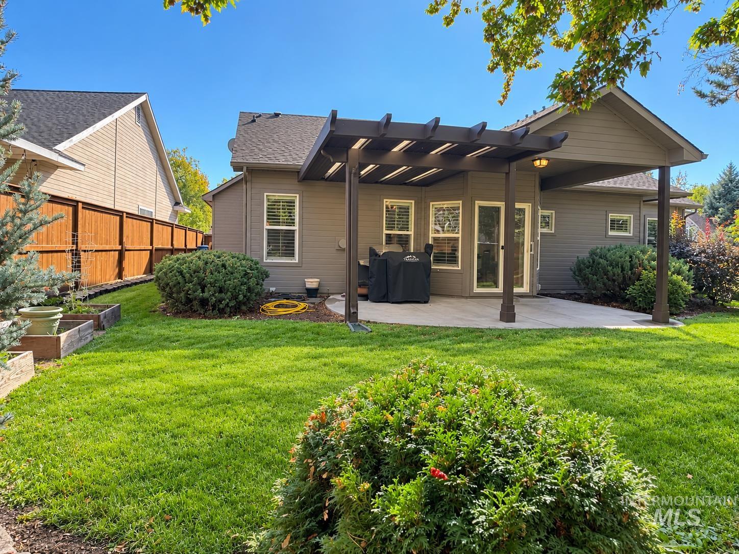 3917 North Waterloo Way Boise, ID 83713 - Photo 22 of 24 Modern home with a covered patio featuring a pergola-style roof structure, expansive manicured lawn with mature landscaping, and composite or fiber cement siding exterior