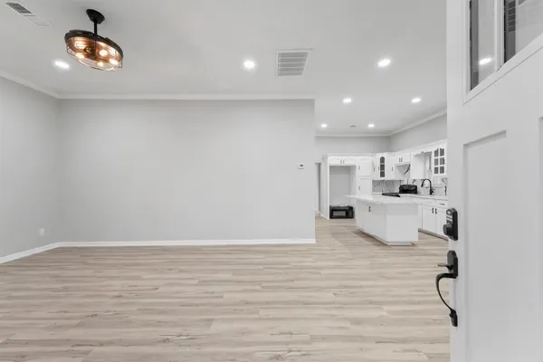 a large white kitchen with kitchen island a stove a sink dishwasher and white cabinets with wooden floor