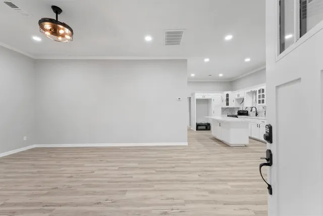 a large white kitchen with kitchen island a stove a sink dishwasher and white cabinets with wooden floor