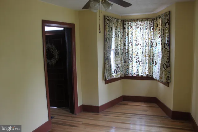 an empty room with wooden floor closet and windows