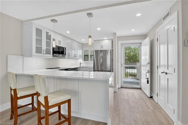 a kitchen with kitchen island granite countertop a table chairs refrigerator and microwave