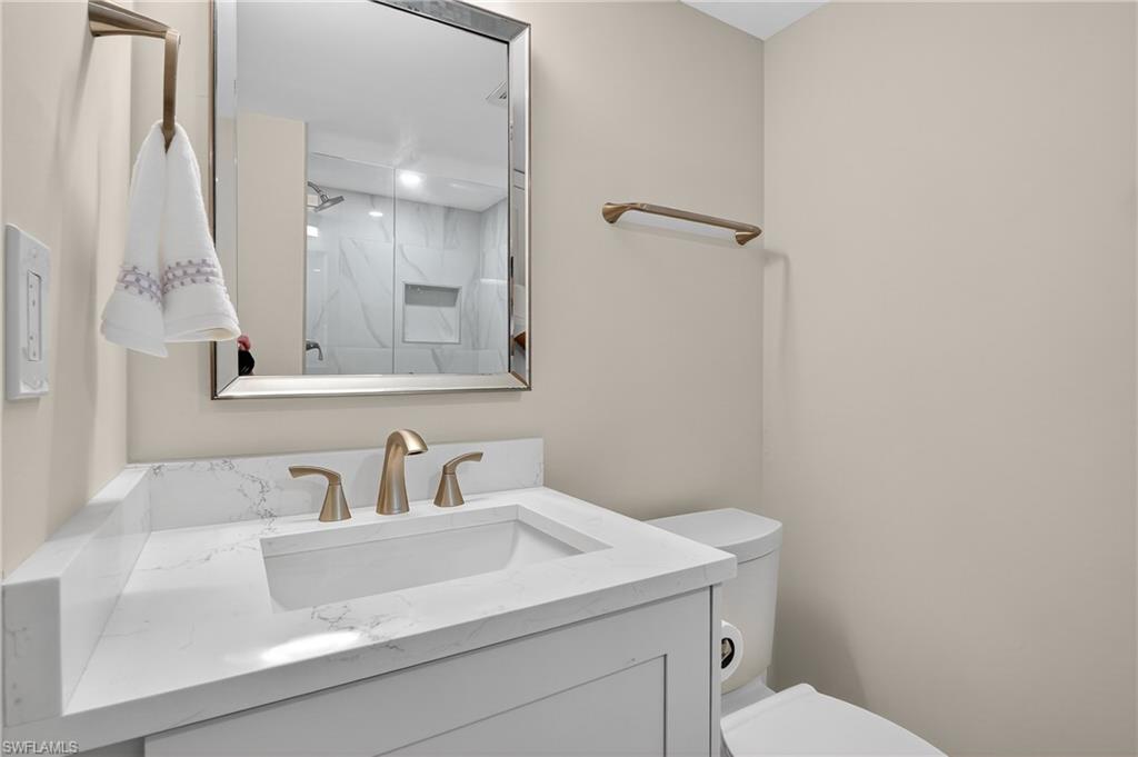 29 High Point Circle East, Unit 204 Naples, FL 34103 - Photo 20 of 29 a bathroom with a sink a toilet and a mirror