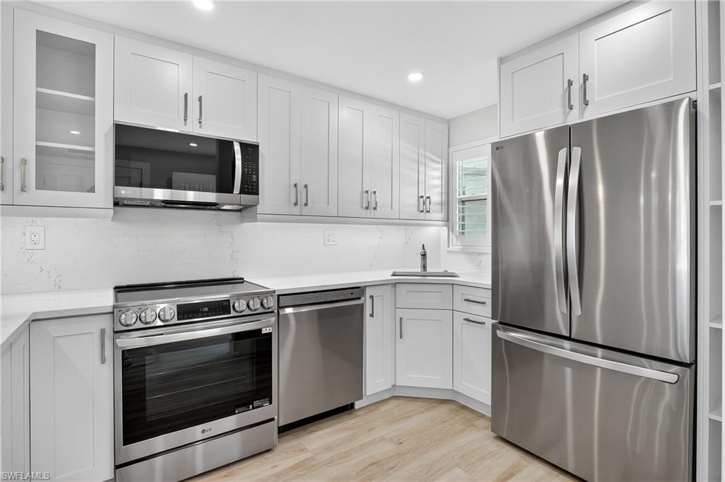 29 High Point Circle East, Unit 204 Naples, FL 34103 - Photo 4 of 29 a kitchen with cabinets stainless steel appliances and wooden floor