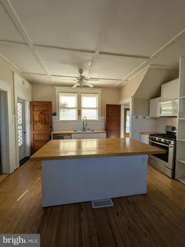 a large kitchen with stainless steel appliances granite countertop a stove and a wooden floors