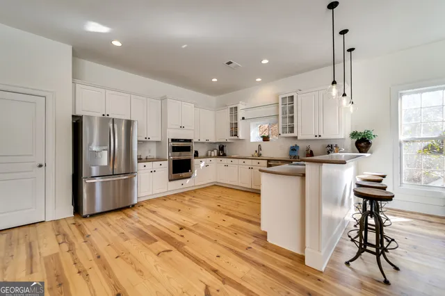 a kitchen with kitchen island a refrigerator and a stove top oven