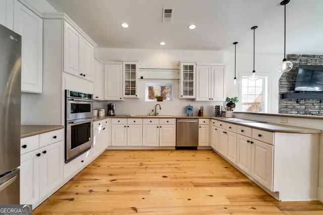a large white kitchen with stainless steel appliances sink and cabinets