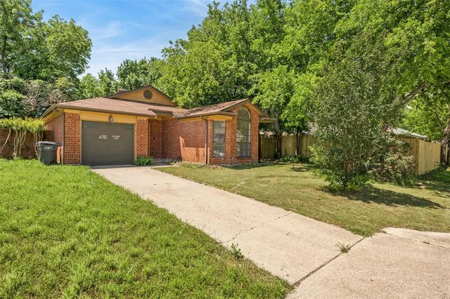 a front view of a house with a garden and trees