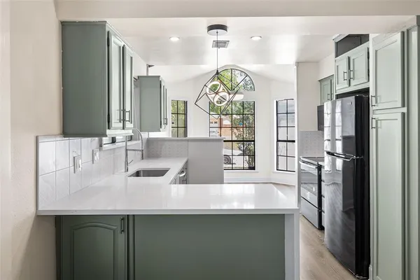 a kitchen with stainless steel appliances a sink a refrigerator a counter space and a window