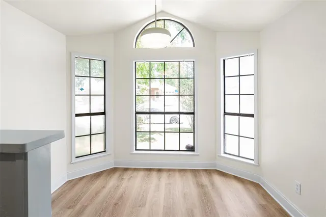 an empty room with wooden floor windows and chandelier