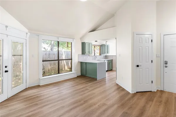 an empty room with wooden floor and a kitchen