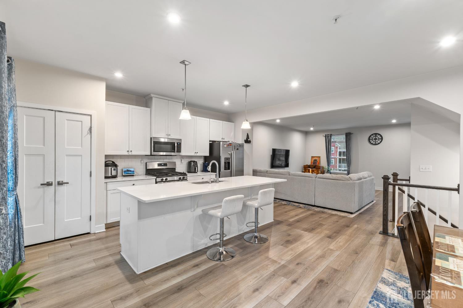 74 Anchor Way Cliffwood, NJ 07721 - Photo 8 of 35 a large white kitchen with kitchen island a stove a sink a refrigerator and white cabinets with wooden floor