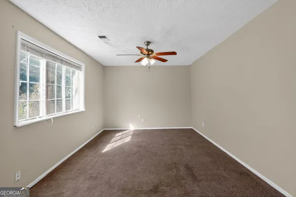 an empty room with windows and fan