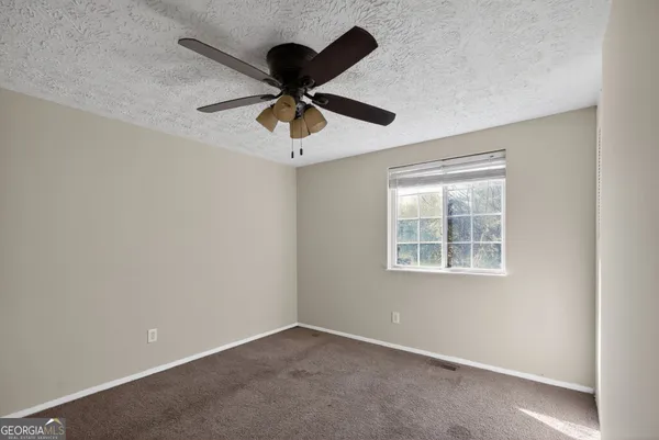 an empty room with a window and a fan
