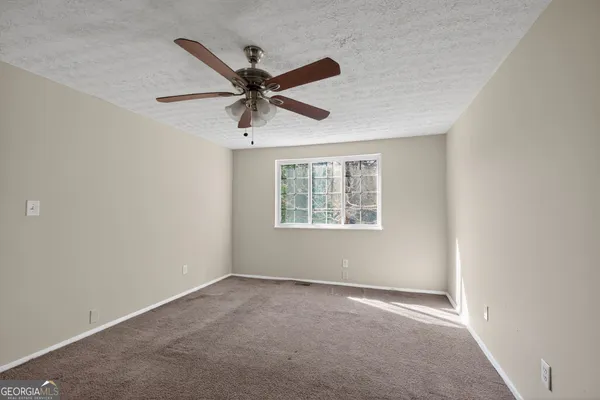 an empty room with a window and a fan