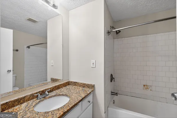 a bathroom with a granite countertop sink a mirror and a bathtub