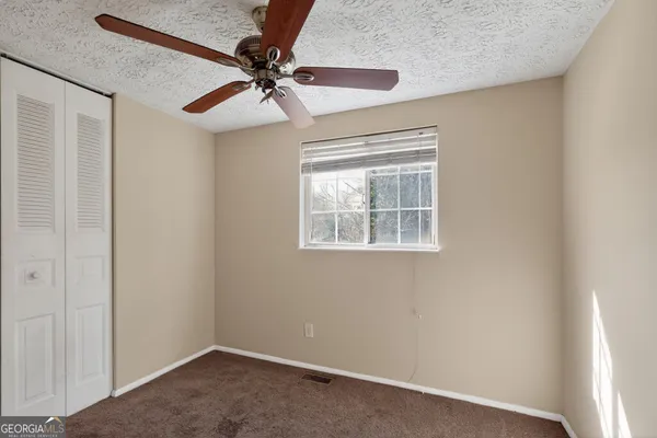 an empty room with a window and a fan