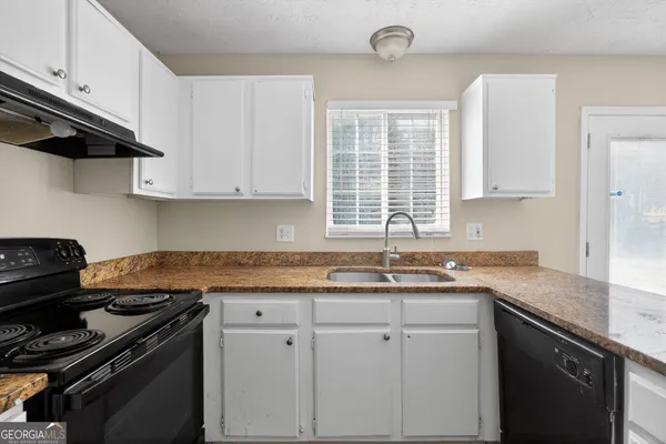 a kitchen with granite countertop a sink stove and cabinets