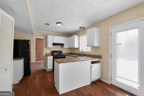 a kitchen with stainless steel appliances granite countertop a stove top oven a refrigerator a sink and dishwasher with wooden floor