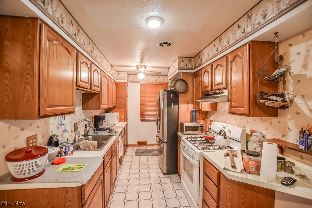 29947 Regent Road Wickliffe, OH 44092 - Photo 6 of 16 Kitchen featuring a textured ceiling, brown cabinets, light countertops, white appliances, and light tile floors