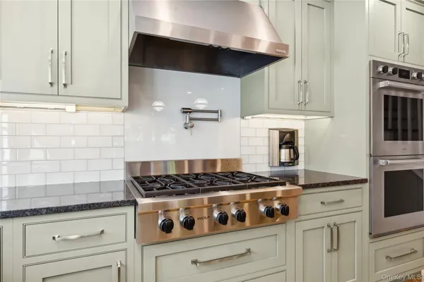 a kitchen with stainless steel appliances granite countertop white cabinets and a stove a oven with wooden floors