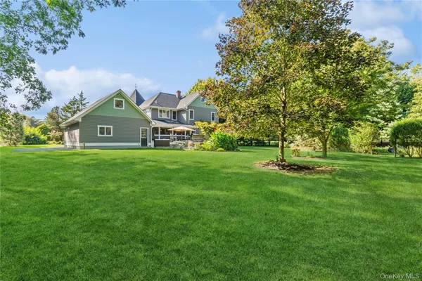 a view of a big house with a big yard and large trees