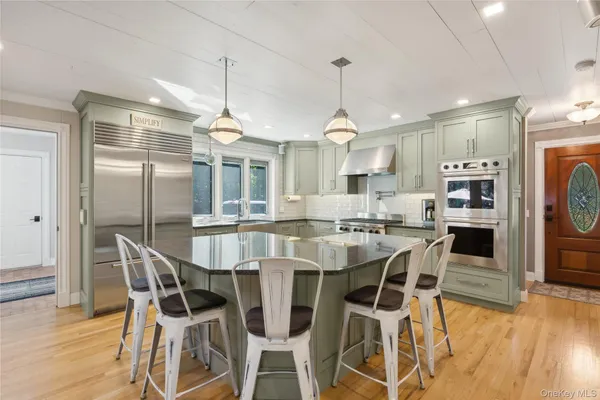 a kitchen with stainless steel appliances kitchen island granite countertop a dining table chairs and white cabinets