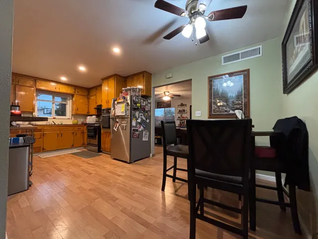 a kitchen with stainless steel appliances kitchen island granite countertop a table chairs and a refrigerator