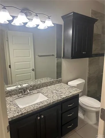 a bathroom with a granite countertop sink a toilet and a mirror