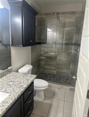 a bathroom with a granite countertop sink a toilet and shower