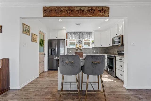a kitchen with kitchen island a dining table chairs cabinets a sink and a window