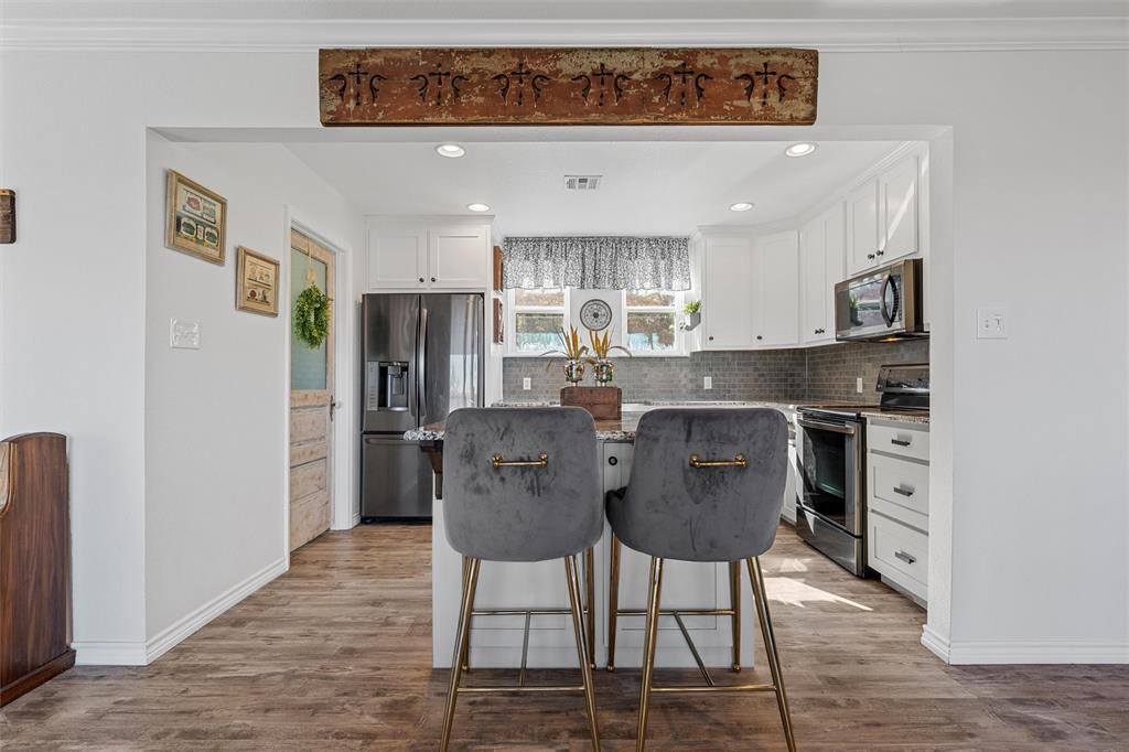 1307 Range Road China Spring, TX 76633 - Photo 11 of 40 a kitchen with kitchen island a dining table chairs cabinets a sink and a window