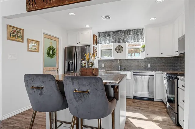 a kitchen with stainless steel appliances granite countertop a table chairs in it and a window