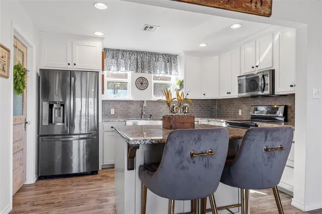 a kitchen with stainless steel appliances granite countertop a refrigerator a stove a sink and a microwave